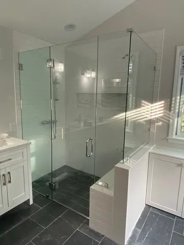 Frameless glass shower doors with a 90-degree angle and chrome hardware on a white tile shower by Glass Doctor of Raleigh