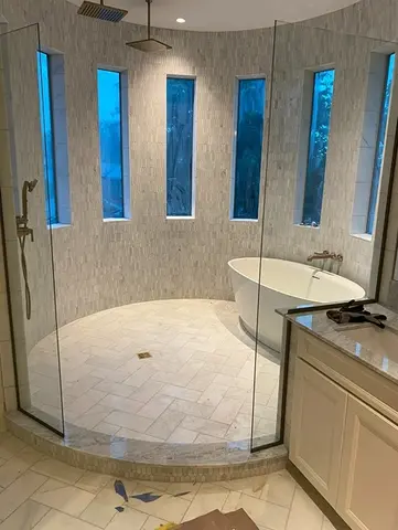 A round shower enclosure with a tub and tall narrow windows and glass splash panels from Glass Doctor of Nashville.