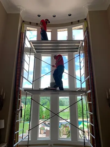 Professional window installers from Glass Doctor of Nashville installing glass in a tall bay window.