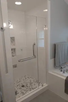 A frameless glass swing door with chrome towel bar and hardware on a white tile shower from Glass Doctor of Raleigh