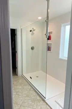A white tile shower with frameless glass splash panel by Glass Doctor of Raleigh