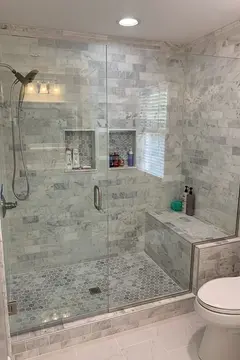 A gray-tiled shower with a frameless glass enclosure and a swinging door installed by Glass Doctor of Nashville.