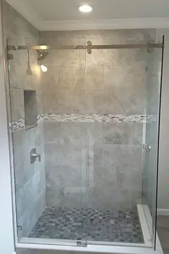 A custom frameless glass shower enclosure with a sliding glass door on a gray tiled shower by Glass Doctor of Tampa Bay.