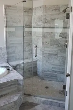A frameless glass shower door installed at an angle on a tiled gray shower by Glass Doctor of Tampa Bay.